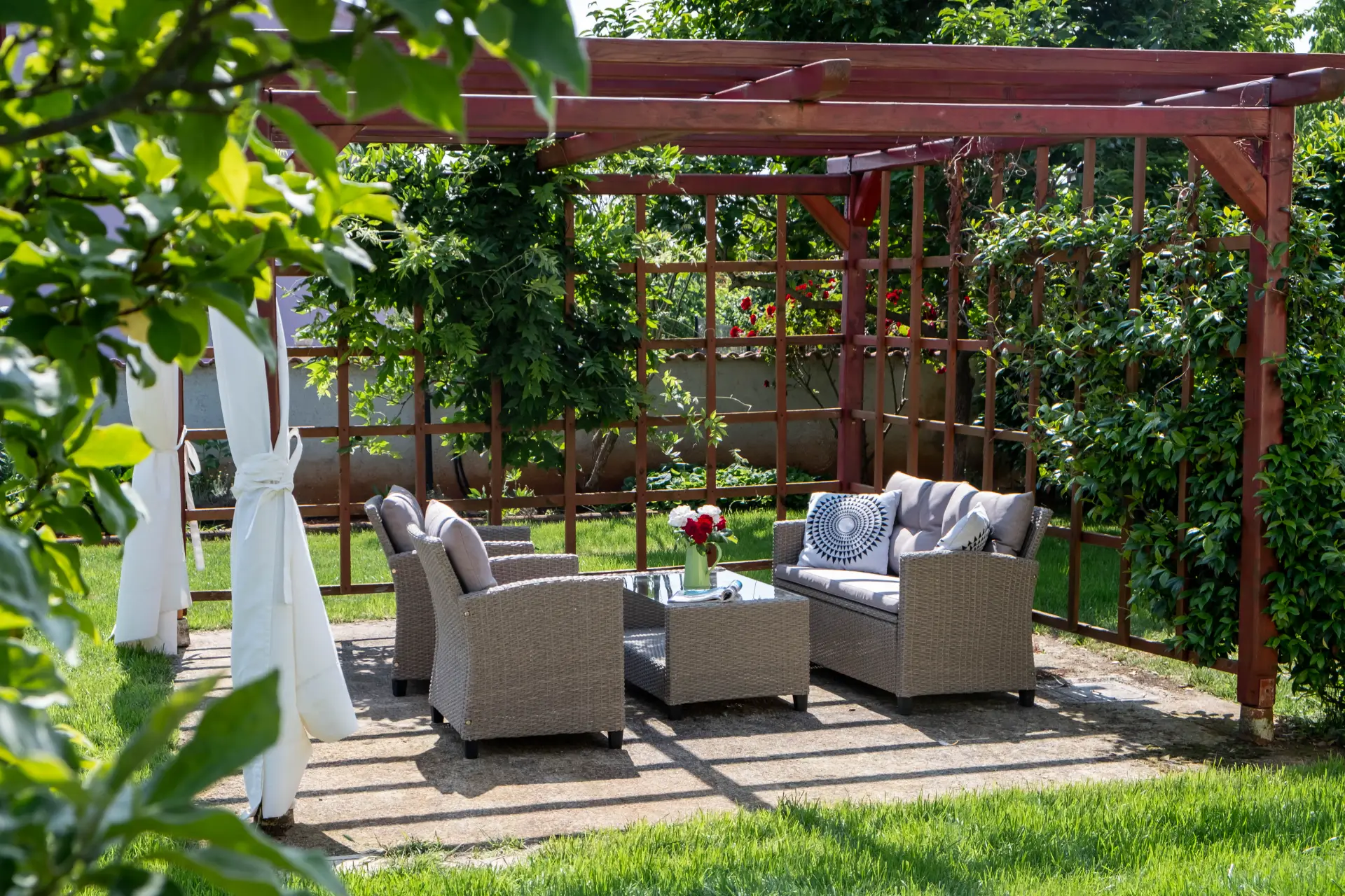 Shaded wooden pergola with comfortable rattan seating in the garden of Villa Rasovic.